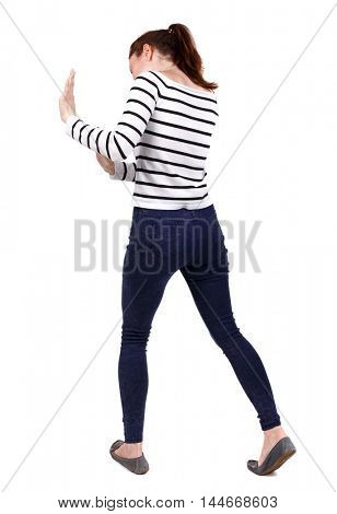 back view of woman pushes wall. Isolated over white background. Girl in a striped sweater pushing something in front of him.
