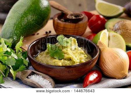 Homemade fresh guacamole sauce and ingredients on table