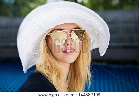 A photo of young woman in white panama hat and sunglasses.