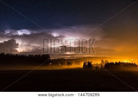 Beautiful view of dramatic dark stormy sky and lightning over small willage at night. Germany, Bavaria.