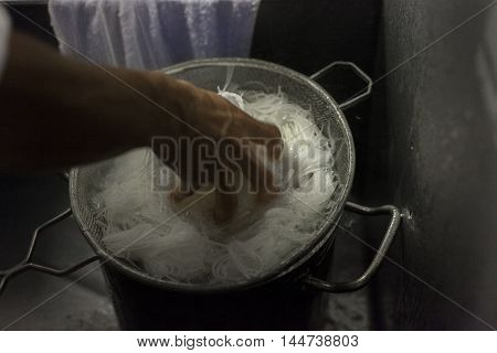 A cook cools hot noodles before dinner service.