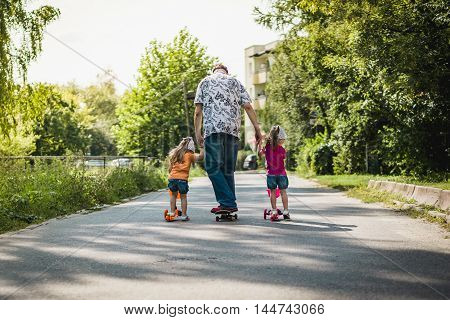 Dad with his daughters on a skateboard and scooter