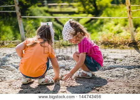 two little girls are playing with stones