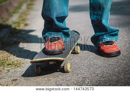 young boy sitting on a skateboard on the street