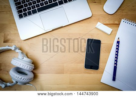desk, computer, paper, phone on a wooden table