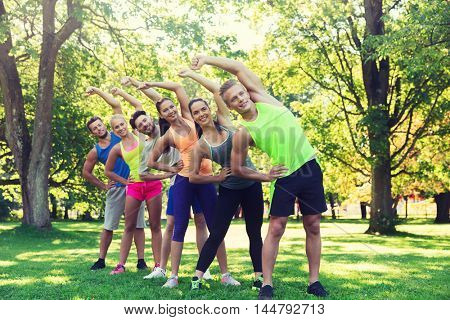 fitness, sport, friendship and healthy lifestyle concept - group of happy teenage friends or sportsmen exercising and stretching hands at boot camp