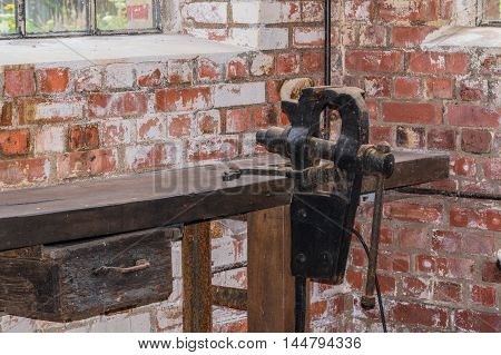 Old black bench vice installed on a workbench.