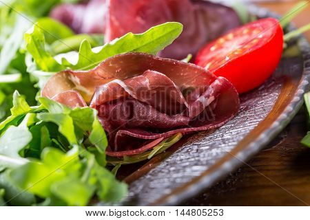Dried beef bresaola. Salad bresaola arugula baby spinach tomatoes lime and cheese parmesan.
