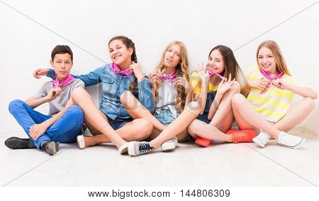 cute smiling tenagers sitting on the floor with legs crossed
