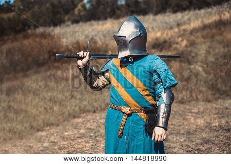 The knight in armor standing holding a sword in hand.