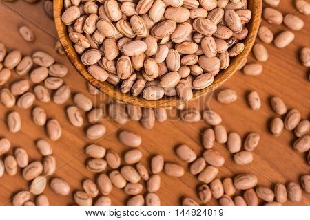 Carioca Beans into a bowl over a wooden table
