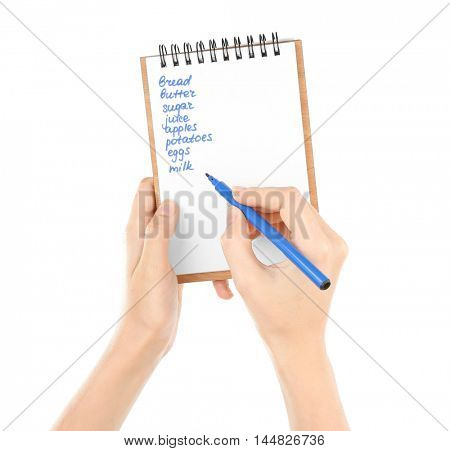 Hands holding pen and notepad with shopping list on white background