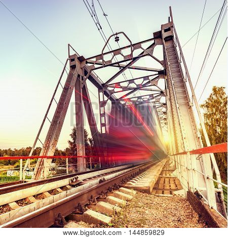 Highspeed train moves fast on the bridge at sunsset.