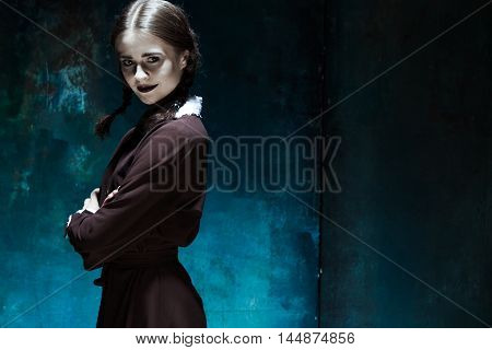 Halloween theme: Portrait of a young smiling girl in school uniform as killer woman against school board . The image in the style of Halloween and Addams family
