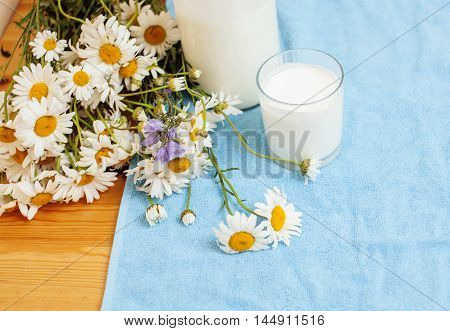 Simply stylish wooden kitchen with bottle of milk and glass on table, summer flowers camomile, healthy foog moring concept noone