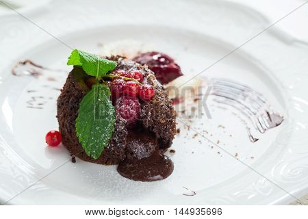 Dessert with red berries. Mint leaves and powdered sugar. Sweet chocolate filling. Dish served with ice cream.