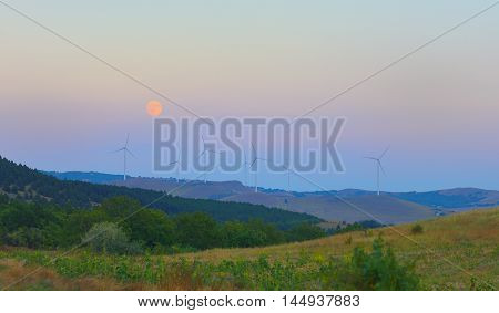 Wind station turbines and full moon at the sky