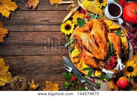 Thanksgiving dinner. Roasted turkey with pumpkins and sunflowers on wooden table
