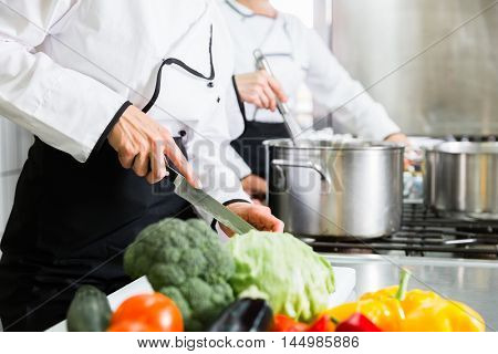 Team of chefs preparing food in canteen kitchen