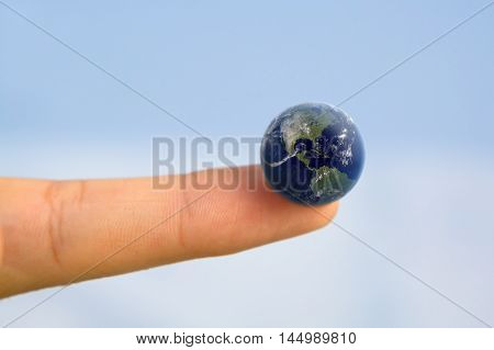 Hand holding earth on fingertip/ World at your Fingertips