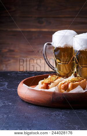 Photo Of Two Glasses Of Beer And Hot Dogs On Wooden Tray On Wooden Background