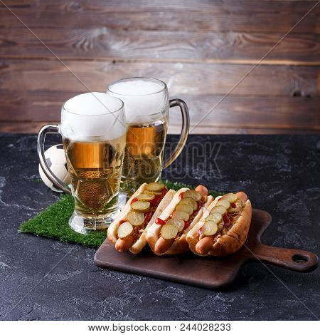 Photo Of Two Mugs Of Foam Beer, Green Grass With Football, Hotdogs On Wooden Board