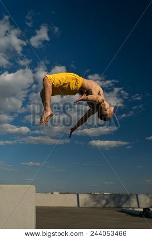 Tricking On Street. Martial Arts And Parkour Elements. Man Flips Back Barefoot. Shooted From Bottom 