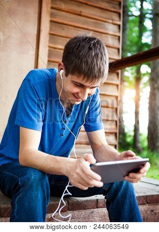 Happy Young Man With A Tablet Computer Near The House Outdoor