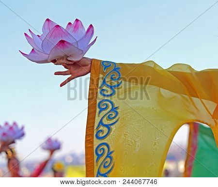 Asian Dancer With Yellow Wide-sleeved Dress Who Is Holding A Lotus Flower During The Outdoor Perform