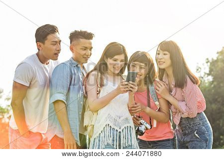 Asian people look something at cellphone with his friends in the park