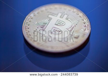 Bitcoin curency DOF on blue glass background. Gold metal curency symbol photo