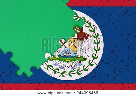 Belize Flag  Is Depicted On A Completed Jigsaw Puzzle With Free Green Copy Space On The Left Side.