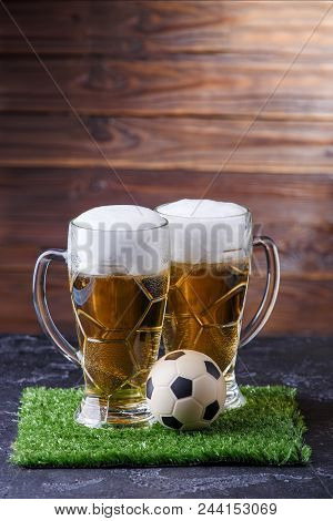 Photo Of Two Beer Mugs, Green Grass With Soccer Ball On Wooden Background