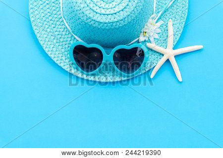 Beach Accessories Including Starfish, Blue Sunglasses And Cyan Beach Hat On Cyan Paper Background Fo