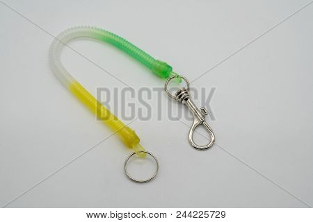 Green And Yellow Key Chain Ring And Silver Metal Hook With Stretchable Spiral String Isolated On Whi