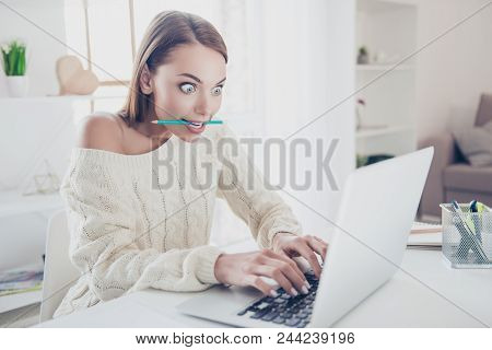 Portrait Of Astonished Big-eyed Woman Holding Pen In Teeth Typing On Keypad Keyboard Using Wifi Inte