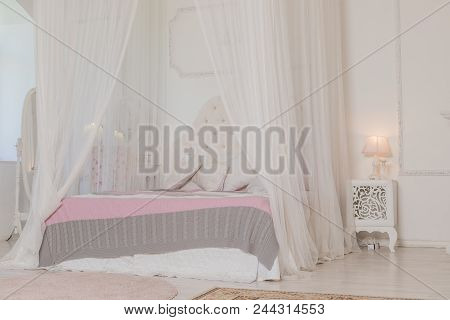 Bedroom In Soft Light Colors With A Wooden Floor. Big Comfortable Four Poster Double Bed In Elegant 