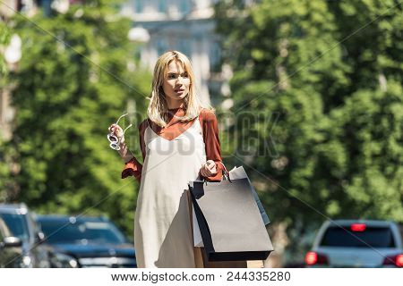 Beautiful Stylish Blonde Girl With Sunglasss And Shopping Bags Looking Away On Street
