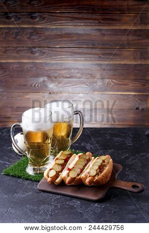 Photo Of Two Mugs Of Foam Beer, Green Grass With Football, Hotdogs On Wooden Board