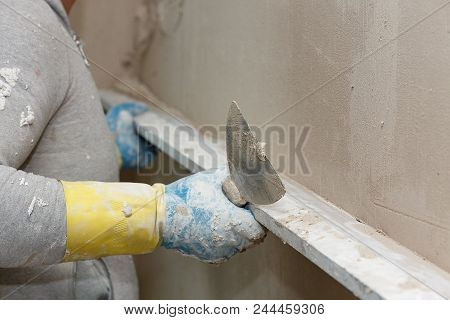 The Process Of Leveling Raw Plaster On The Wall Using A Board.