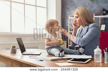 Happy Mother Working At Office With Her Baby. Young Woman Talking On Phone While Spending Time With 