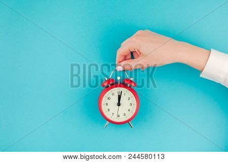 Creative Flat Lay Concept Top View Of Woman Hand In White Shirt Holding The Red Vintage Alarm Clock 
