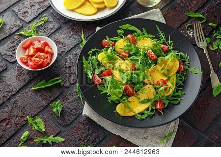 Polenta Salad With Sea Salt, Tomatoes, Green Rocket In A Black Plate