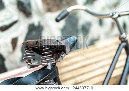 An Old Bicycle Seat With A Spring Shock Absorber. Vintage Bicycle On The Stone Wall Background.