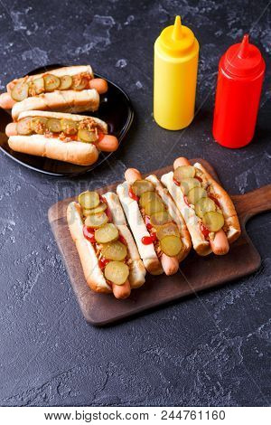 Photo On Top Of Hotdogs On Plate And Board At Table With Ketchup And Mustard