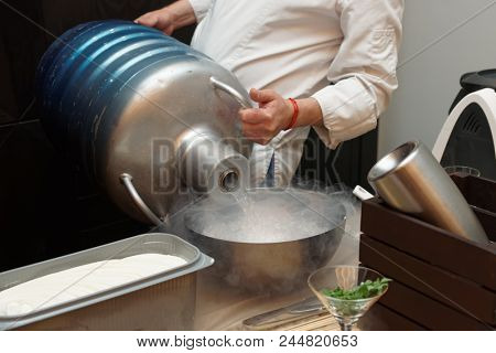 Chef is pouring liquid nitroden from a large Dewar flask, molecular cooking