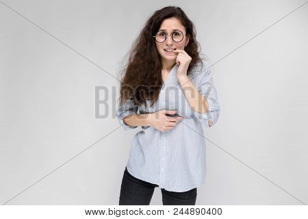 Happy Young Girl In A Light Blouse And Dark Pants. The Girl Is Worried.