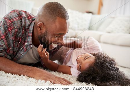 Father Tickling Daughter As They Play Game In Lounge Together