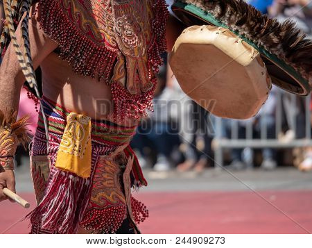 A Man Dressed In Traditional Aztec Garb Beats On A Drum During A March