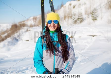 Photo of sporty woman with skis and sticks in winter